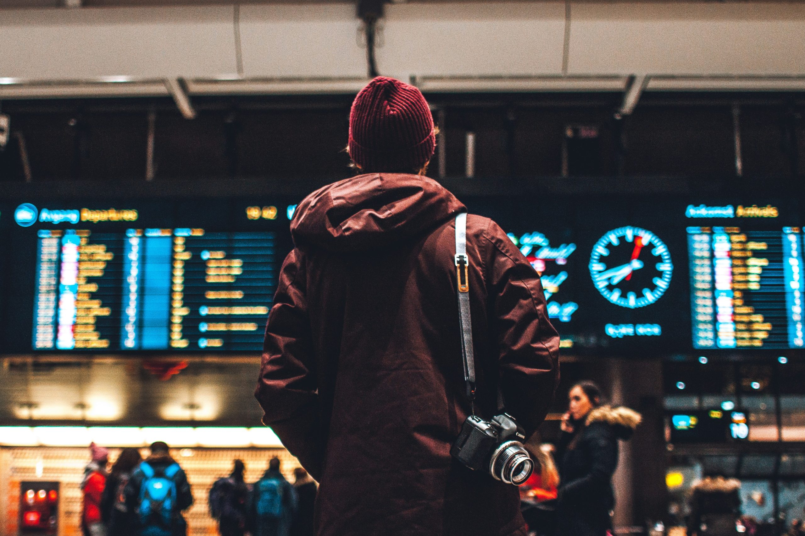 Hombre en un aeropuerto mirando pantalla con software de gestión de viajes para agencias, representando el uso de tecnología en la gestión de reservas.